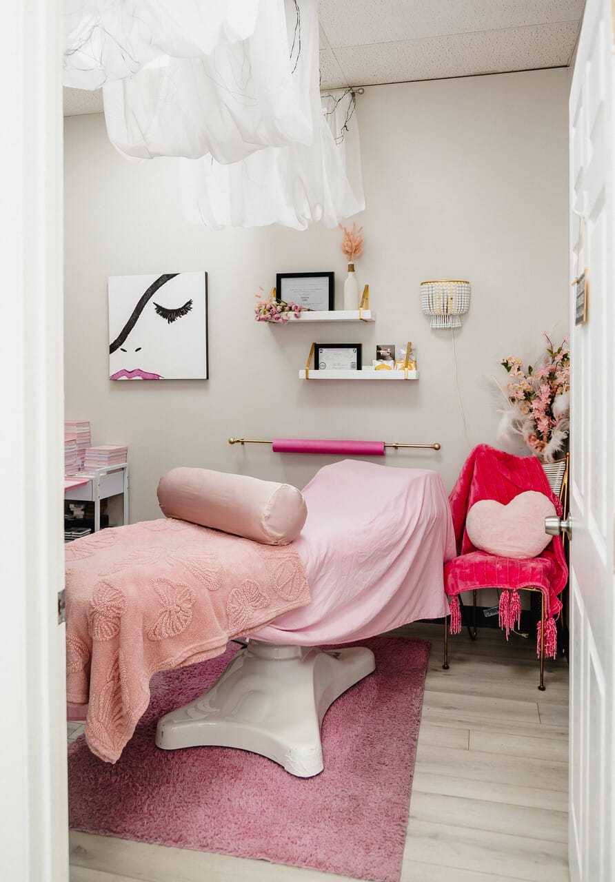 Cozy beauty salon room with a pink massage table and elegant decor.